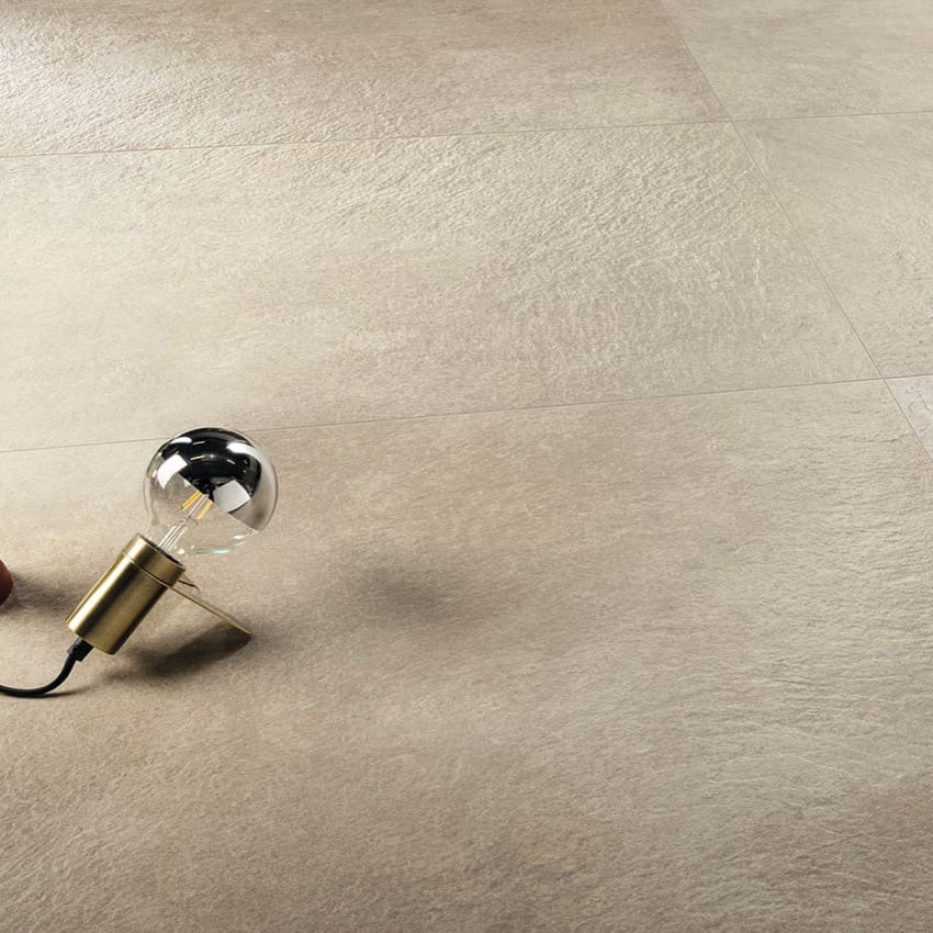 Absolute Clay 600x600mm porcelain floor tiles in warm beige with a subtle stone texture, styled with a decorative brass pendant bulb lamp.