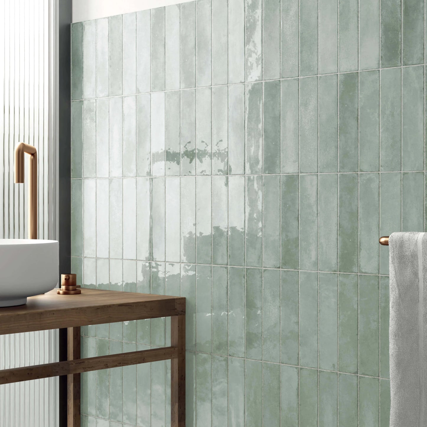 Acquarello Fossil Glossy 60x246mm sage green ceramic wall tiles installed vertically in a modern bathroom with a wooden vanity, vessel sink, and brass fixtures.