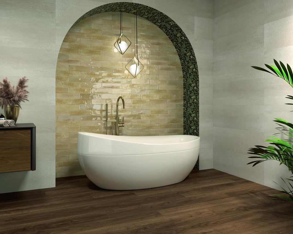 Agadir Arena 70x280mm glossy warm beige wall tiles installed inside an arched bathroom niche with a freestanding white bath and brass pendant lights.