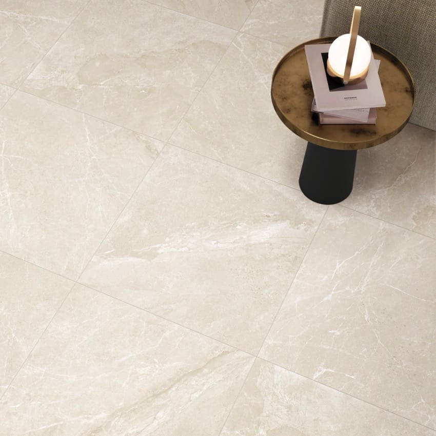 Alpen Stone Warm Lappato 600x1200mm tiles installed as a living room floor in warm beige with subtle marble veining, styled with a brass side table.