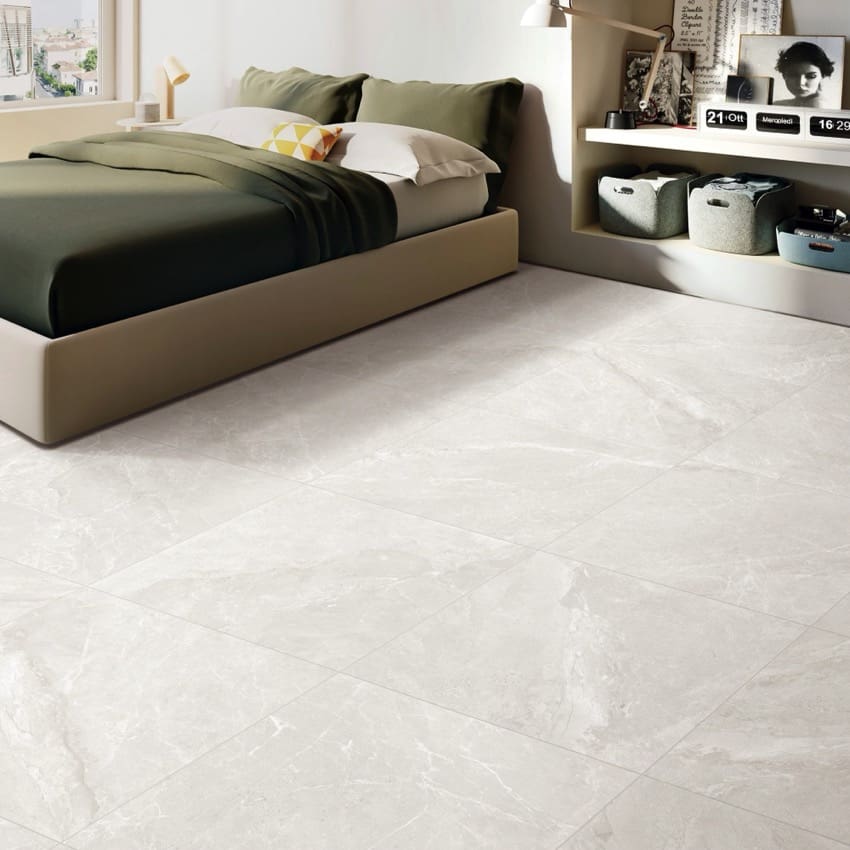 Alpen Stone White Lappato 600x1200mm porcelain tiles installed as a bedroom floor, showcasing a soft grey marble effect finish beneath a modern upholstered bed and built-in shelving unit.