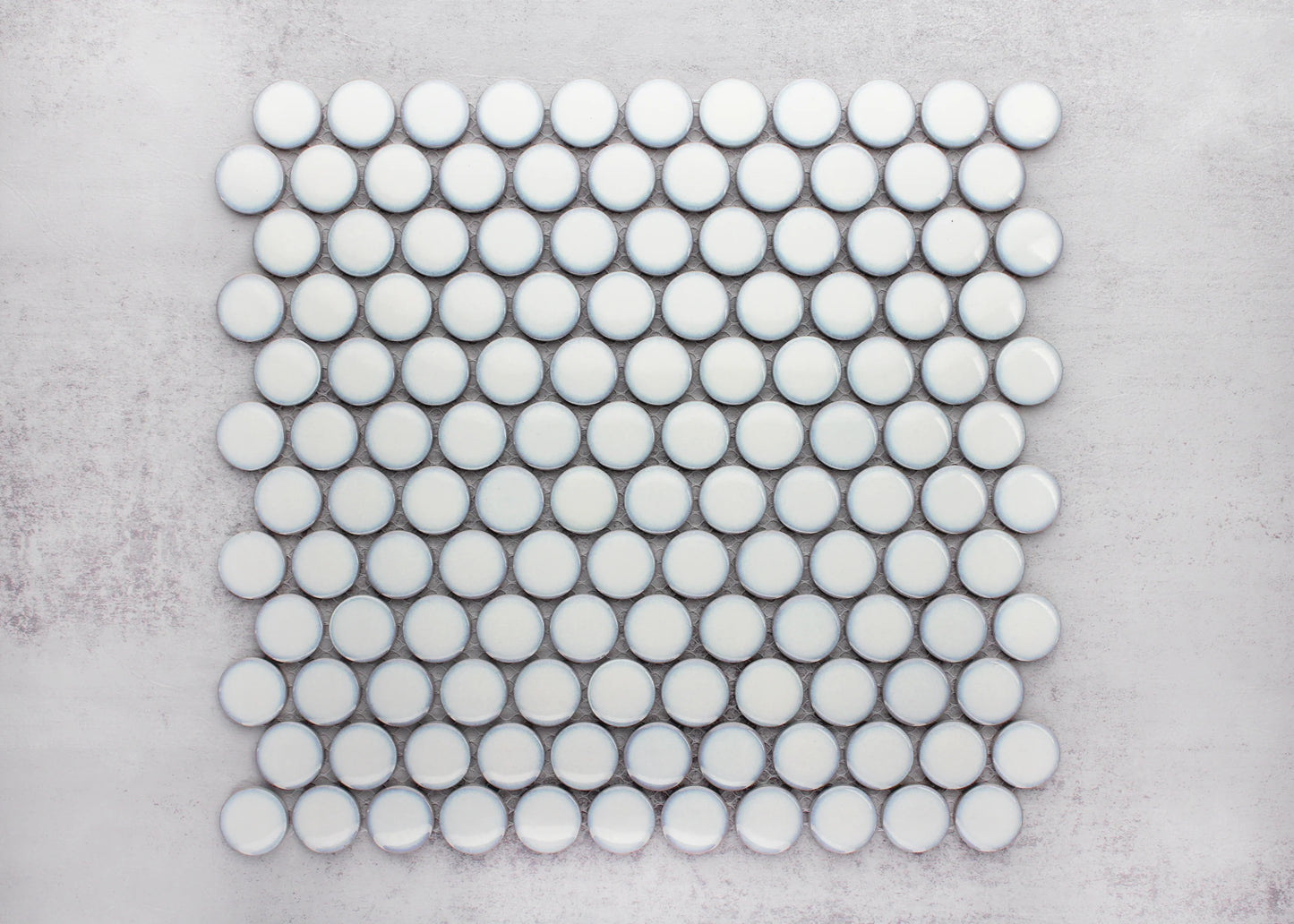A flat lay pack shot of Antique White Gloss Glazed Porcelain Penny Round 28mm Diameter tiles arranged in a neat mosaic sheet against a grey background.