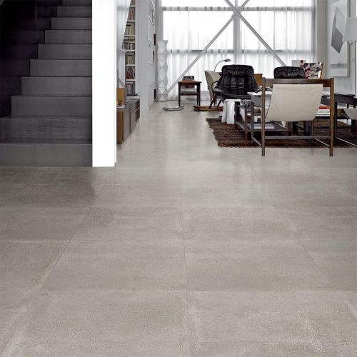 Argyle Stone Cement Rectified 600x600 grey floor tiles installed in a modern open-plan living room with staircase and contemporary furniture.