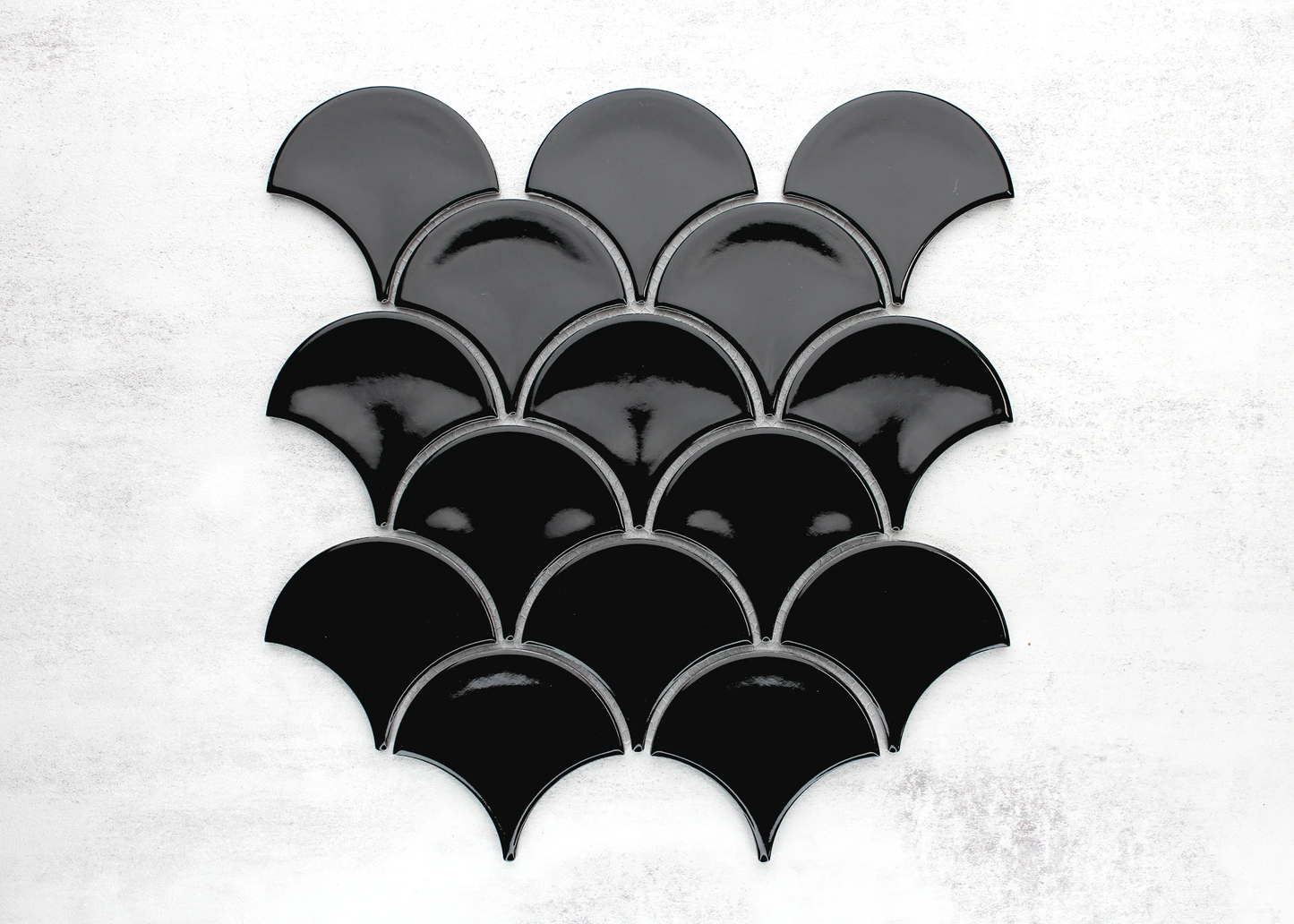 Pack shot of Black Gloss Glazed Porcelain Fishscale 95x87mm tiles arranged in an overlapping scale pattern with a high-gloss finish.