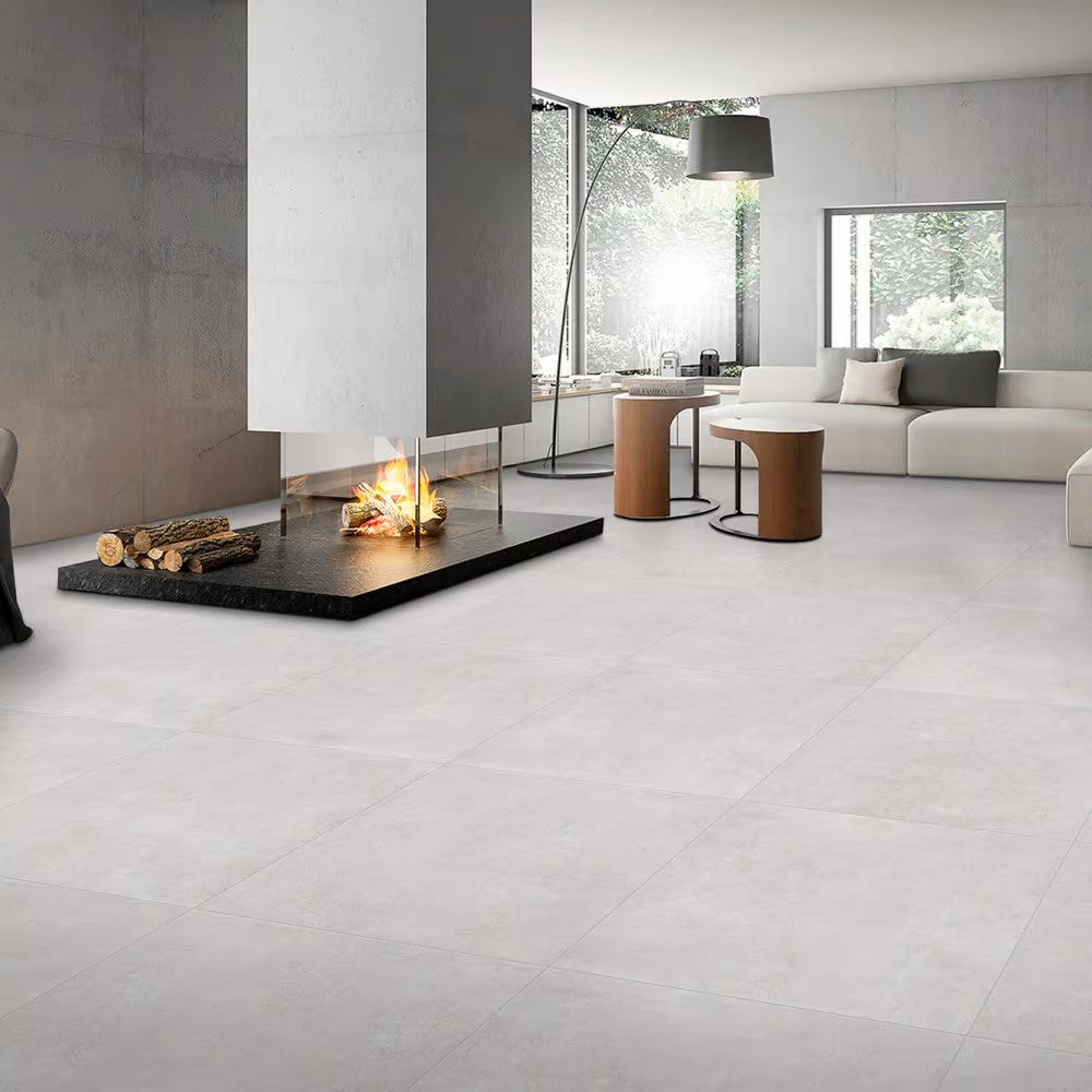 Boston Silver Matt 600x600mm floor tiles installed in a spacious modern living room featuring a statement fireplace and contemporary white sofa.