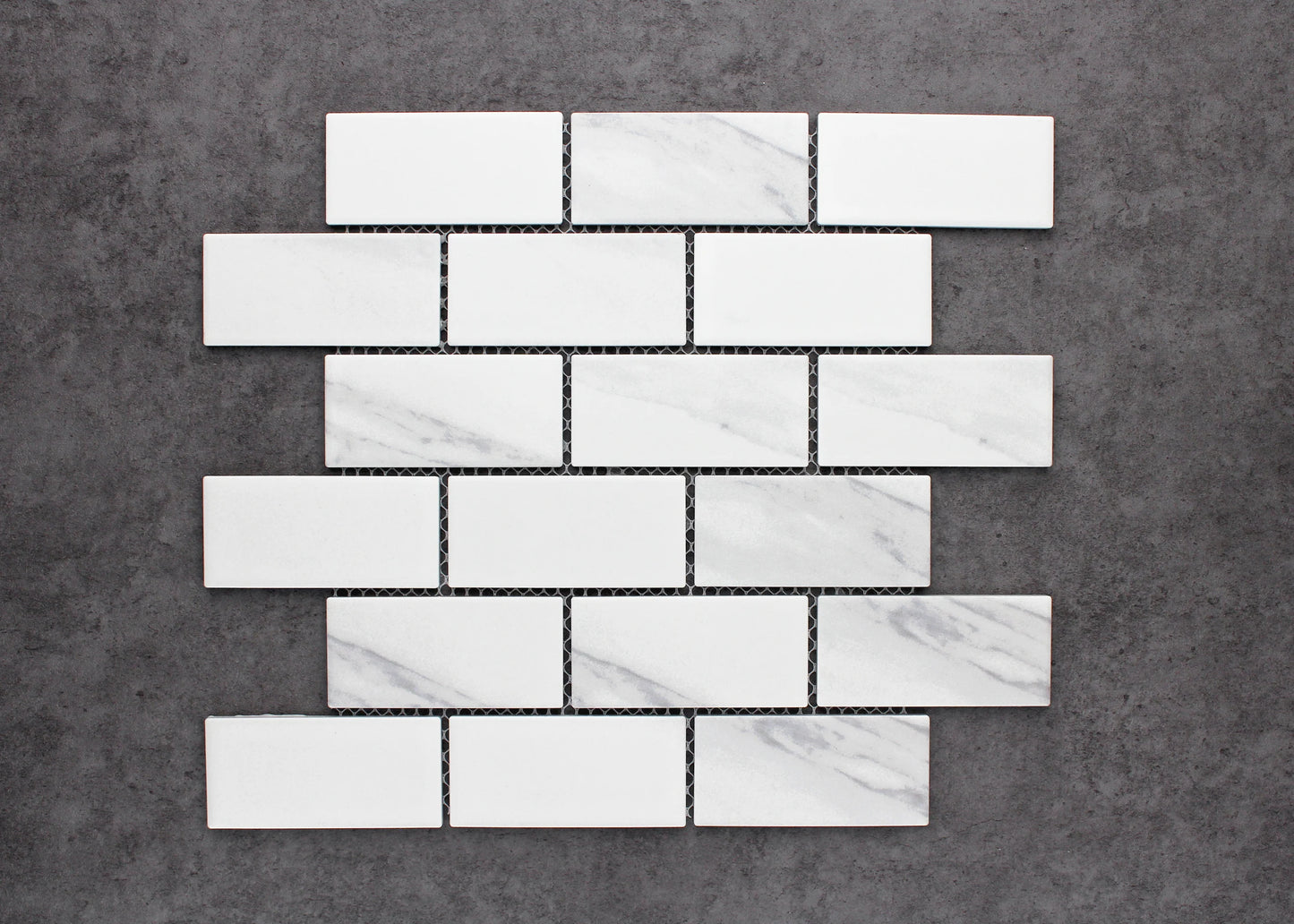 Pack shot of Carrara Look Matte Porcelain Glazed Brickbone 45x95mm tiles arranged in a classic brick-bond pattern, showing white matte finish with subtle grey marble veining.