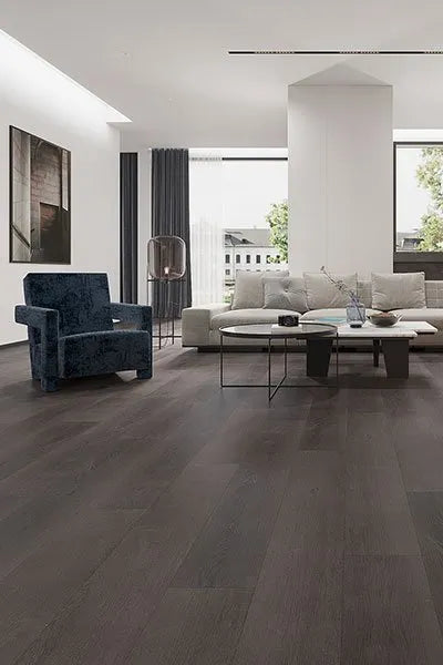 Charcoal Elegant SPC Hybrid 6.5mm Flooring 5+1.5mm installed in a modern open-plan living room with a grey sofa, blue armchair, and floor-to-ceiling windows.