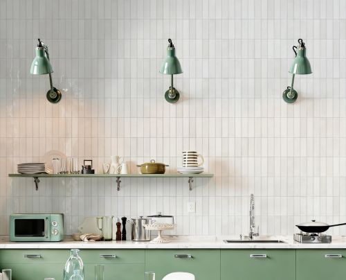 Chroma Pearl Gloss 52x160mm white square tiles covering a bright kitchen wall with sage green cabinets, open shelving, and mint wall sconce lights.