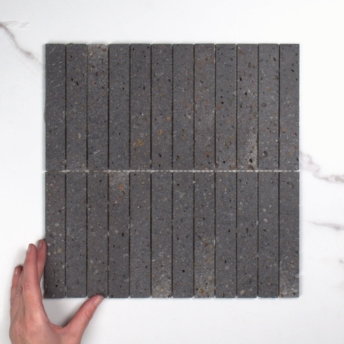 Elementa Travertine Black Finger Mosaic 23x148mm top view, hand for scale