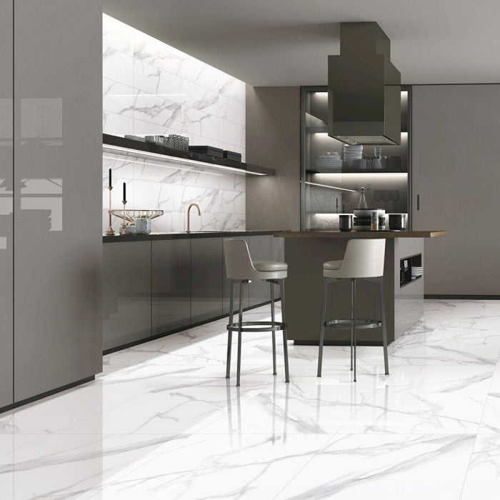 Grey Vein Statuario Polished 600x600mm tiles installed on a modern kitchen floor and splashback, styled with dark grey cabinetry and bar stools.