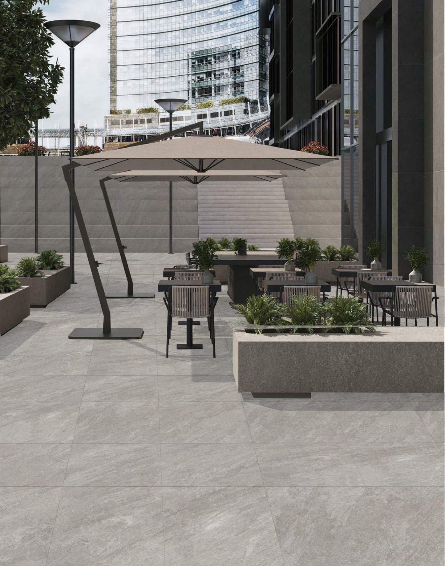 Kora Stone Shale Matt 600x600mm grey porcelain tiles installed on a modern outdoor commercial patio with dining chairs, umbrella, and raised planters.