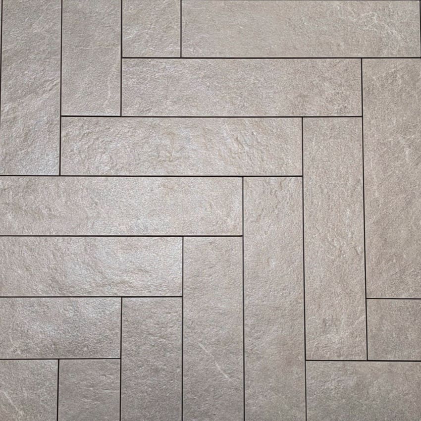 Lava Ash Amber Brick/Subway 75x300mm tiles arranged in a herringbone pattern, showcasing a textured grey stone-effect finish with fine grout lines.