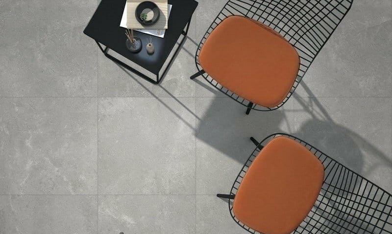 Lusso Grigio Matt 600x600mm tiles installed on an outdoor patio floor with terracotta wire-frame chairs and a black side table.