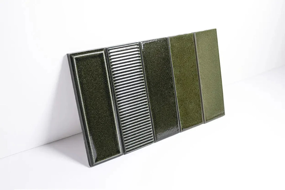 Micare Rim Evergreen Dark Gloss 50x150mm tile sample board displaying five variations including flat gloss, ribbed, and textured finishes in deep forest green.