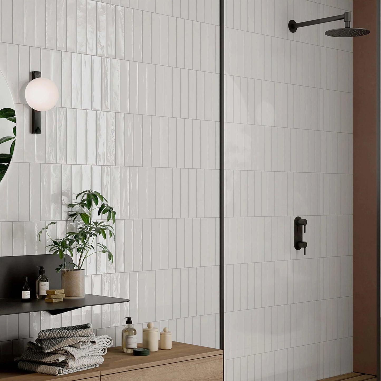 Mojave White Brick 60x250mm glossy white vertical stacked tiles covering a modern bathroom walk-in shower wall with matte black fixtures and globe wall light.