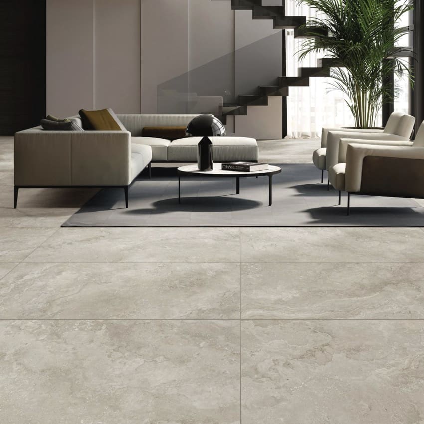 Norcia Travertine Silver Bamboo Feature 600x1200mm tiles installed as a large-format living room floor with modern sectional sofa, round coffee table, and staircase.