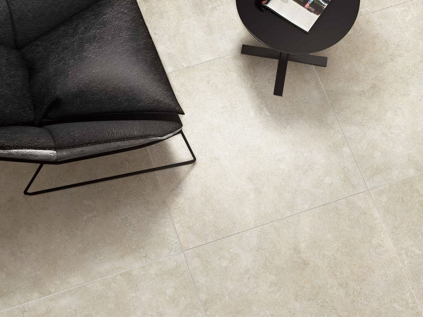 Stella Beige Lappato 600x600mm porcelain floor tiles installed in a modern living room styled with a black leather chair and round side table.