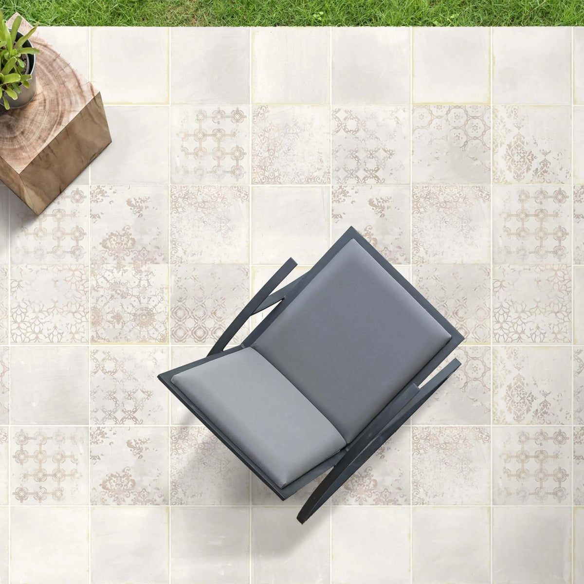 Terracota Blanco Decor 200x200mm patterned floor tiles laid on an outdoor patio styled with a modern grey lounge chair and wooden side table.