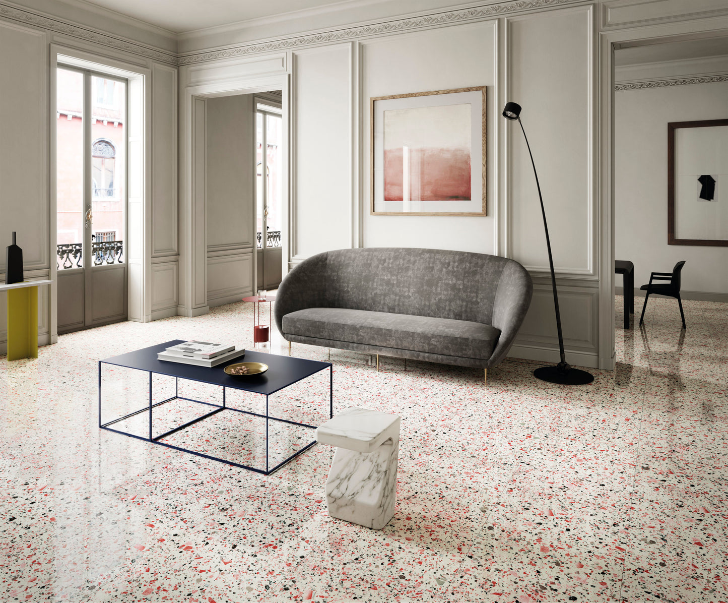Venice Coral 300x600mm Matt Terrazzo Tile installed as a polished living room floor with a grey curved sofa, marble side table, and black arc floor lamp.