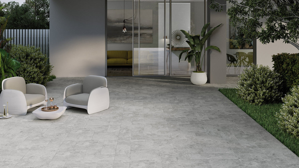 Ventor Grey Modular External tiles laid on a modern outdoor patio featuring contemporary white lounge chairs, lush garden borders, and glass sliding doors.