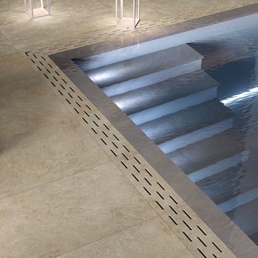 Absolute Clay 600x600mm porcelain tiles installed as a pool surround with linear drainage channel alongside submerged entry steps.