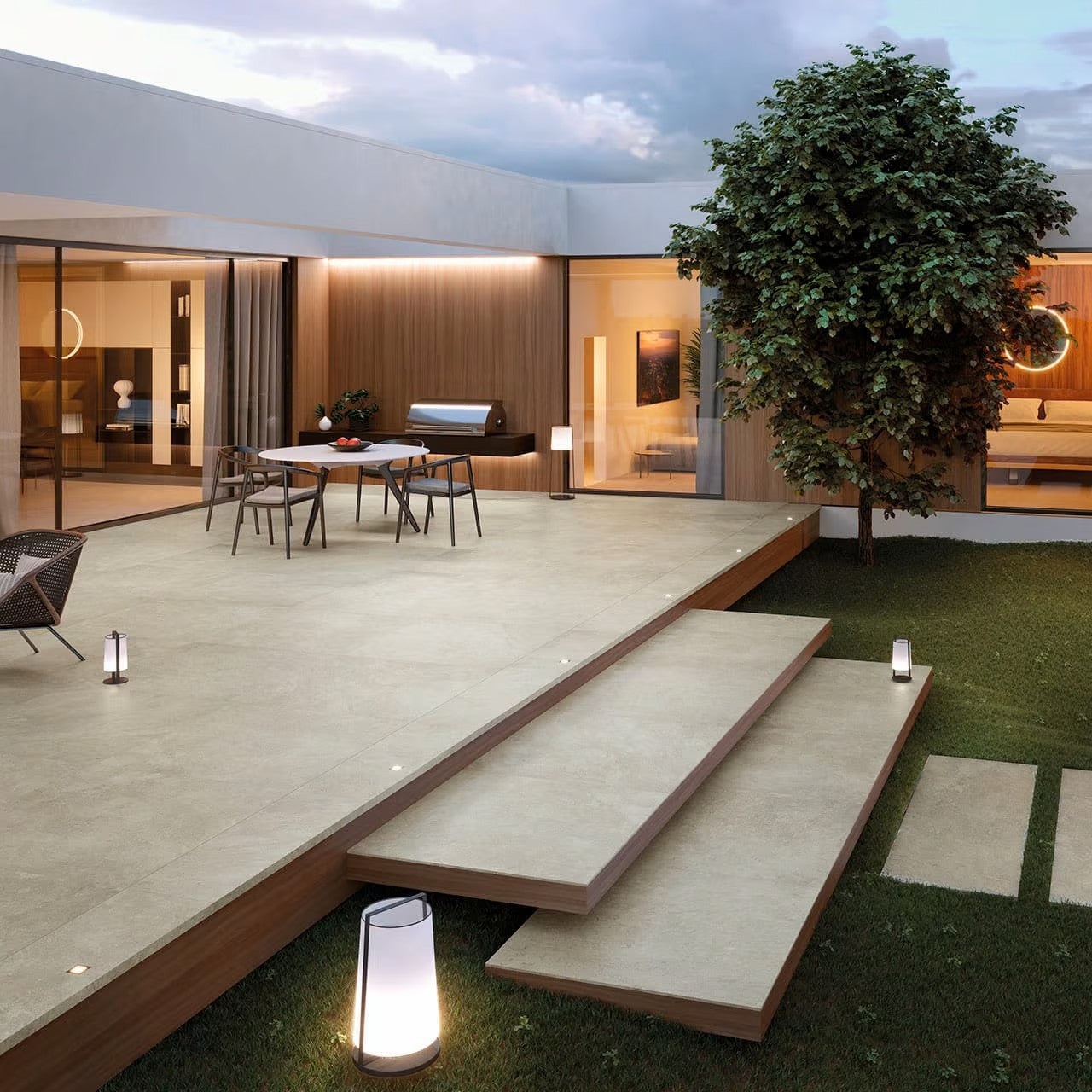 Absolute Moon 600x600mm light beige porcelain tiles laid on a raised modern outdoor patio terrace with timber-edged steps, garden lighting, and open-plan living areas beyond.
