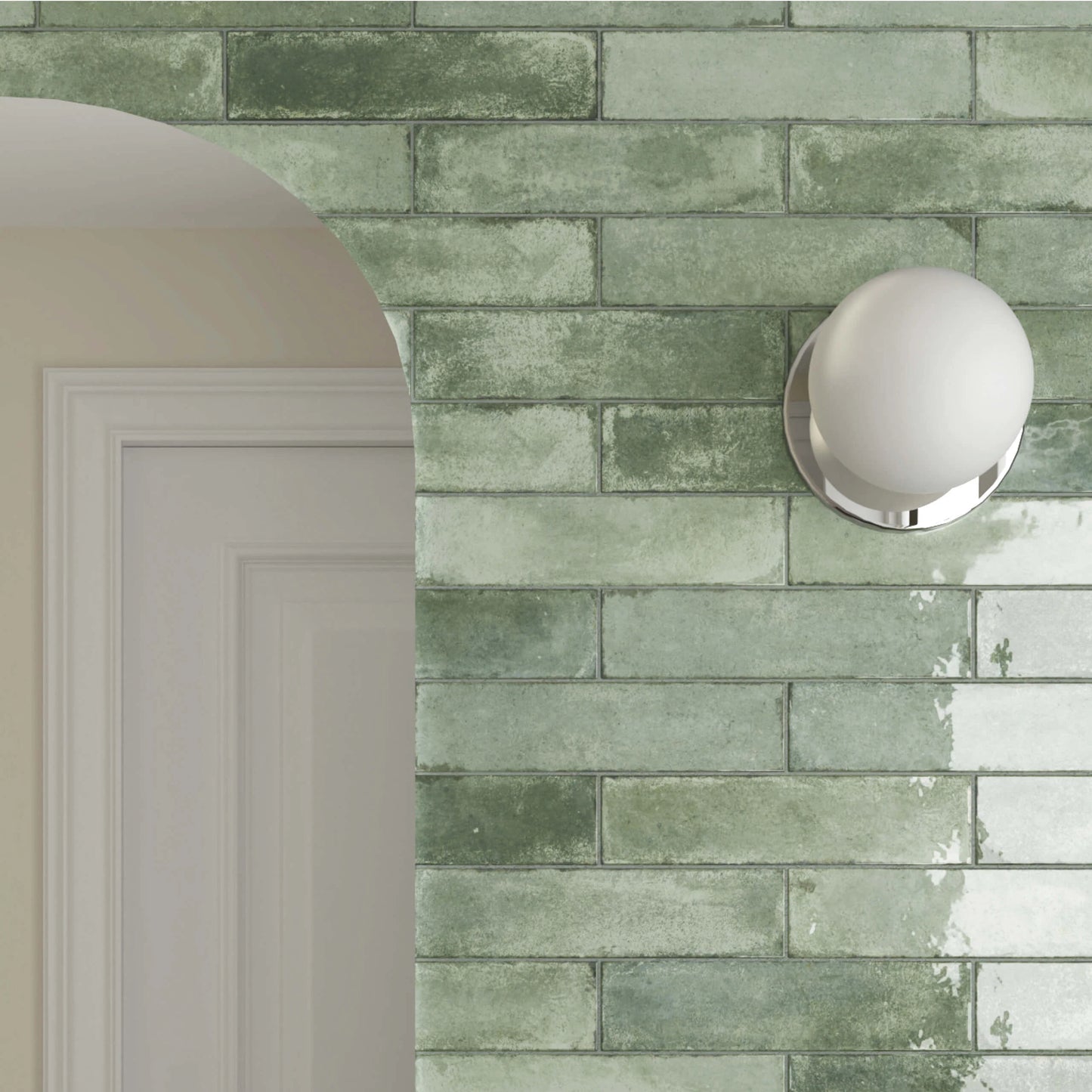 Acquarello Sage Glossy 60x246mm wall tiles in a muted green brick pattern with a chrome globe sconce light and white arched doorway.