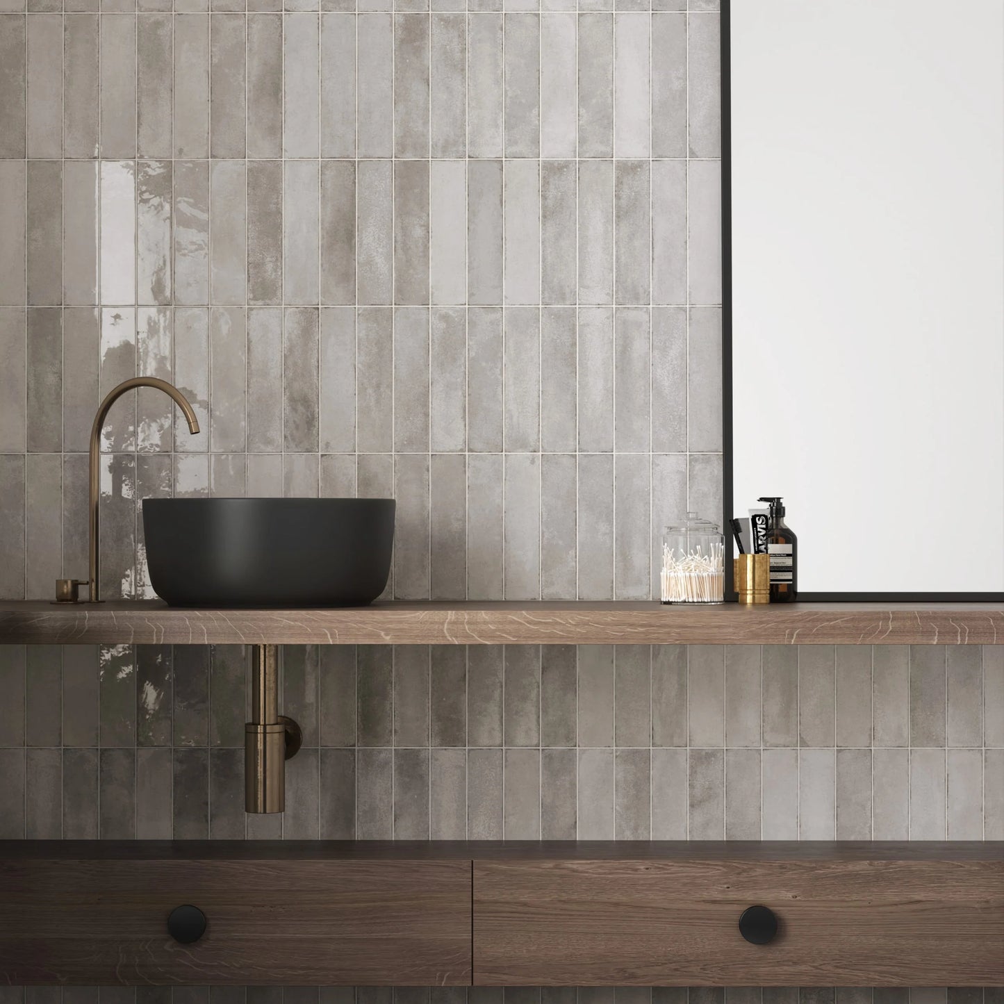 Acquarello Titanio Glossy 60x246mm tiles installed vertically on a bathroom wall behind a matte black vessel sink and warm wood vanity with brass fittings.