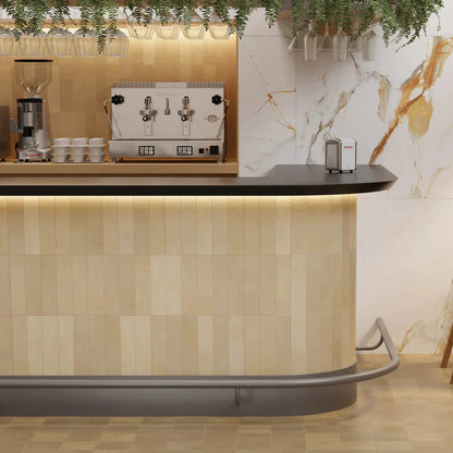 Agadir Cotto Oscuro 70x280mm tiles clad on a curved café bar counter with warm LED underlighting, marble feature wall, and hanging wine glasses above.