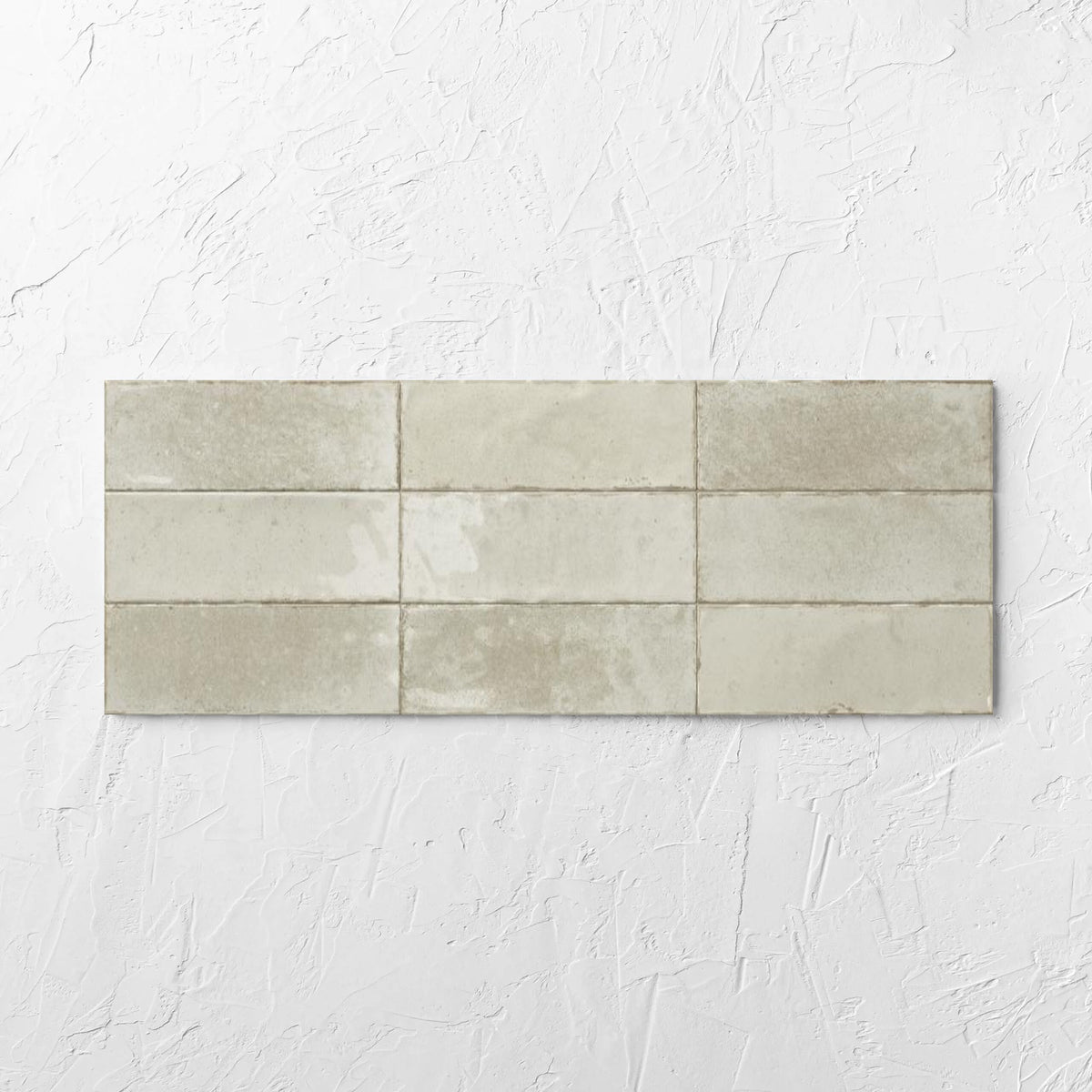 Agadir Ivory 70x280mm tile laid flat on a white rendered wall, showing the ivory ultra-gloss surface