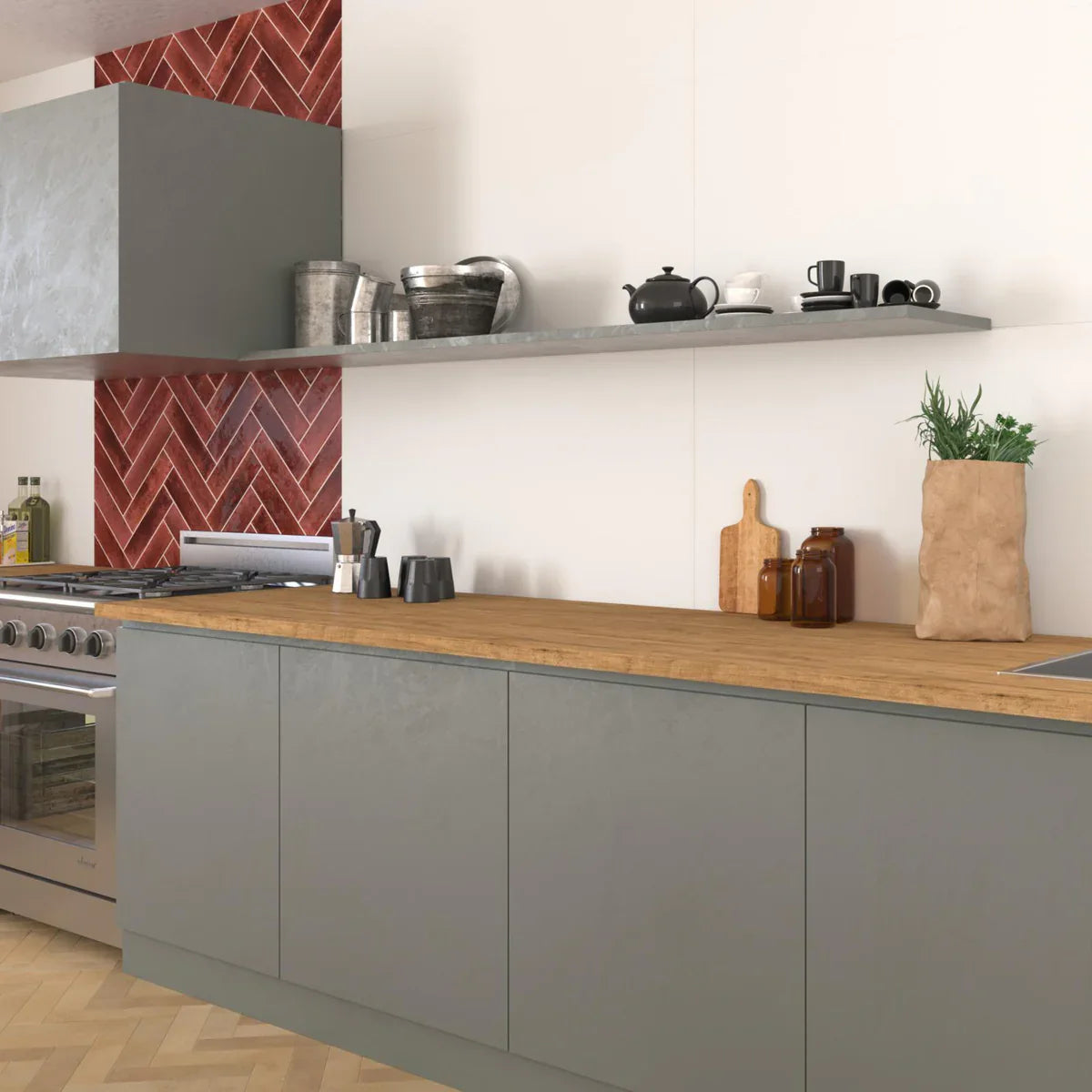 Agadir Lava 70x280mm deep red herringbone tiles form a striking kitchen splashback behind a stainless steel range cooker and grey cabinetry with oak worktop.
