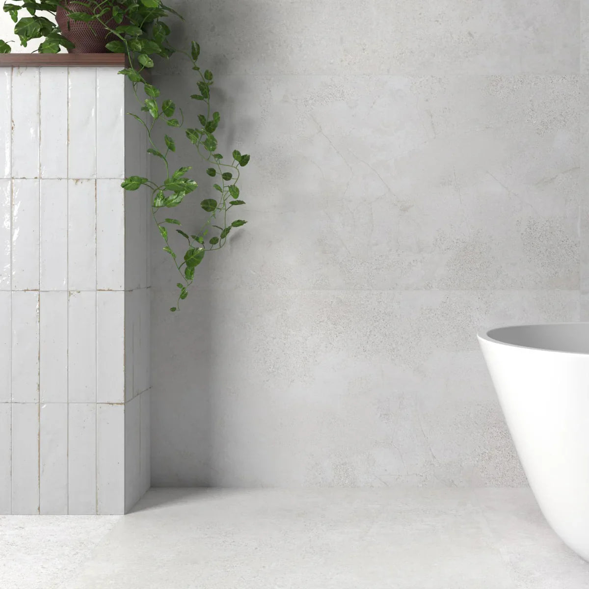 Agadir Niebla 70x280mm white gloss vertical stack tiles on a bathroom feature column beside a freestanding tub and trailing green plant.