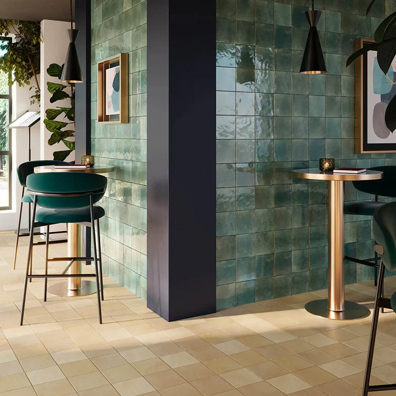 Agadir Selva 70x280mm glossy teal zellige-effect wall tiles installed in a stylish bar with gold pendant lights and velvet bar stools.