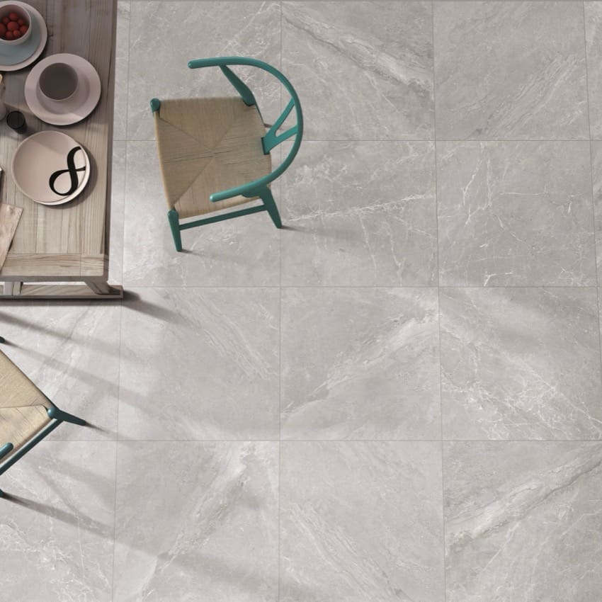 Alpen Stone Grey Lappato 600x1200mm porcelain floor tiles shown in an overhead lifestyle view with teal chairs and a wooden side table.
