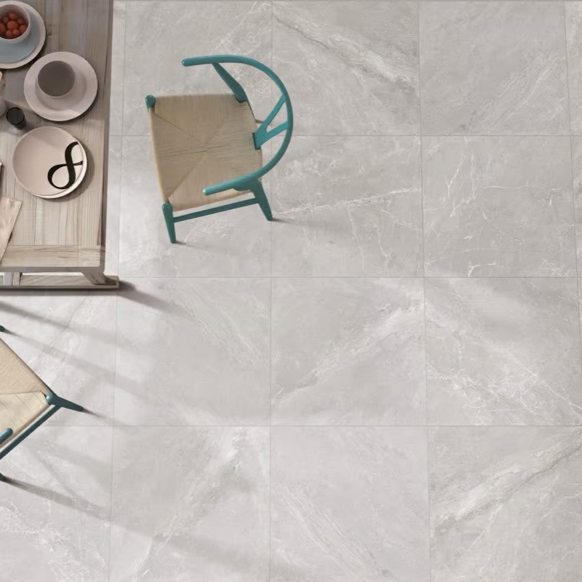 Alpen Stone Grey Lappato 600x600mm tiles installed on a dining area floor, viewed from above with a teal chair and wooden table.