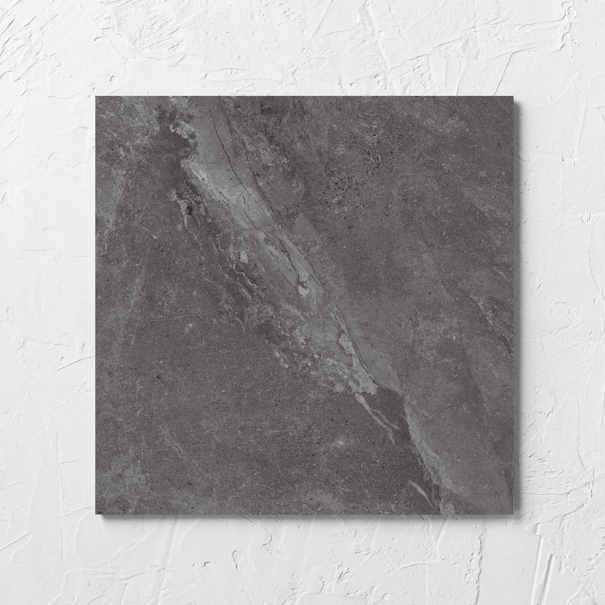 Alpen Stone Smoke 300x300mm tile laid flat on a white rendered wall, showing the smoke surface