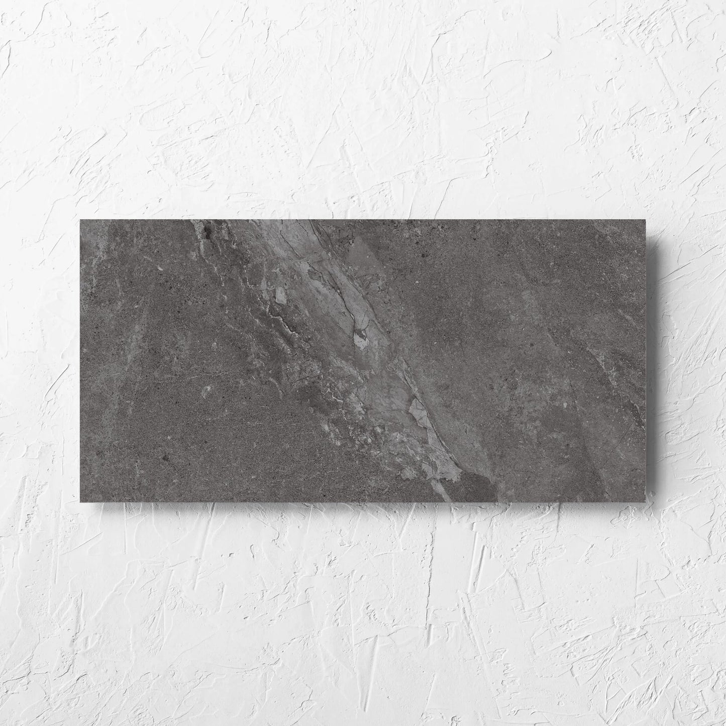 Alpen Stone Smoke 300x600mm tile laid flat on a white rendered wall, showing the smoke surface