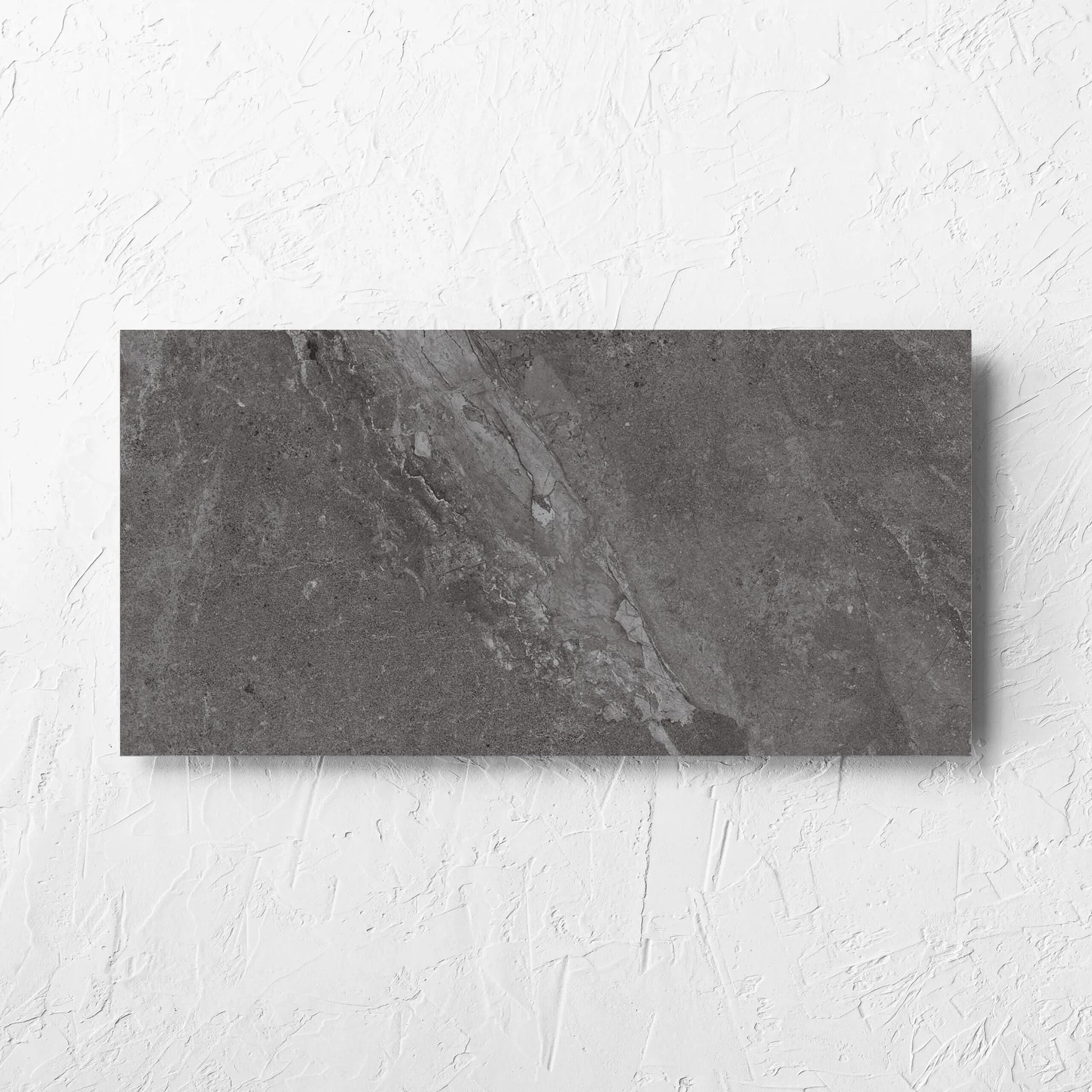 Alpen Stone Smoke 300x600mm tile laid flat on a white rendered wall, showing the smoke surface