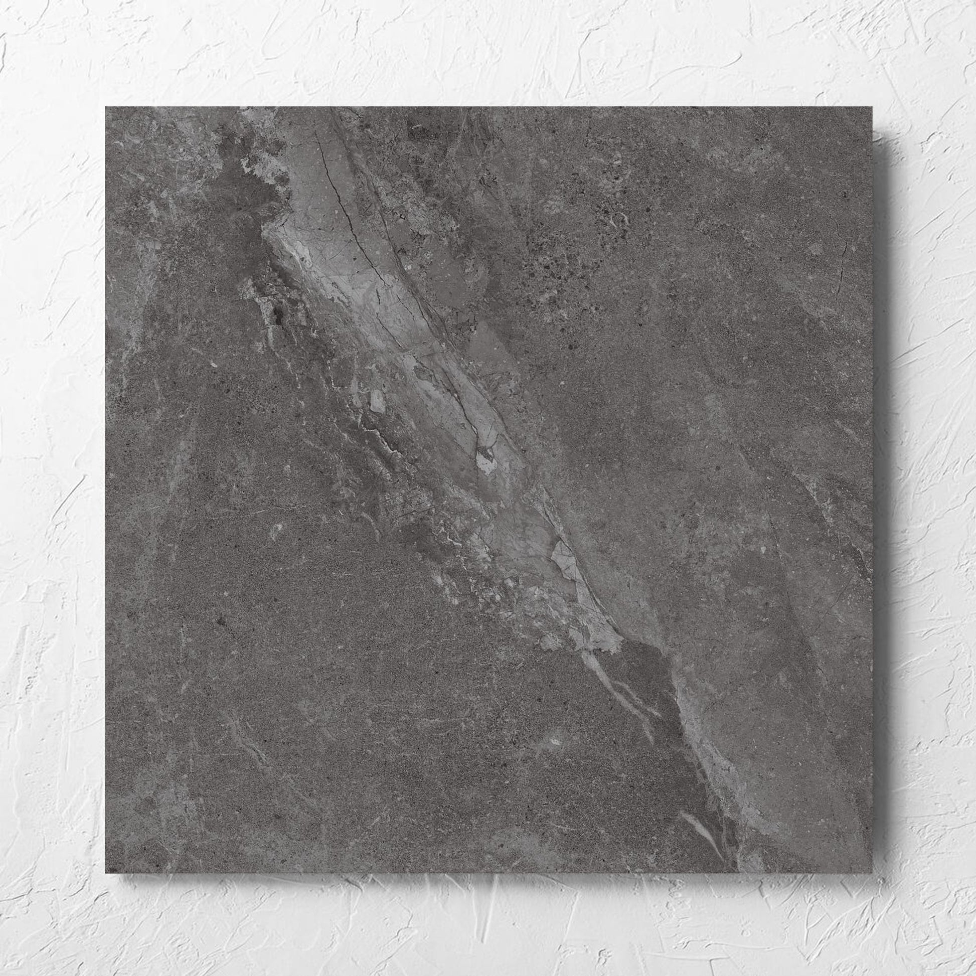 Alpen Stone Smoke Lappato 600x600mm tile laid flat on a white rendered wall, showing the smoke surface
