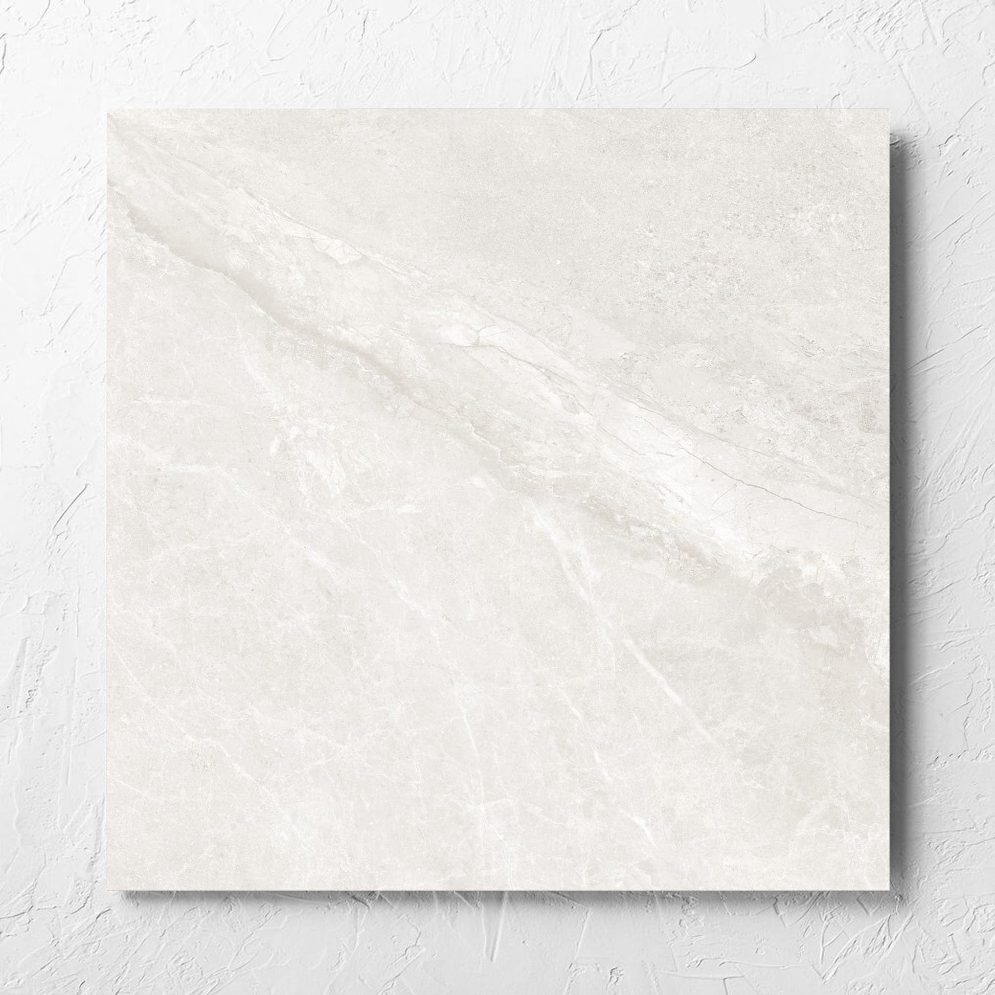 Alpen Stone White 600x600mm tile laid flat on a white rendered wall, showing the tile surface