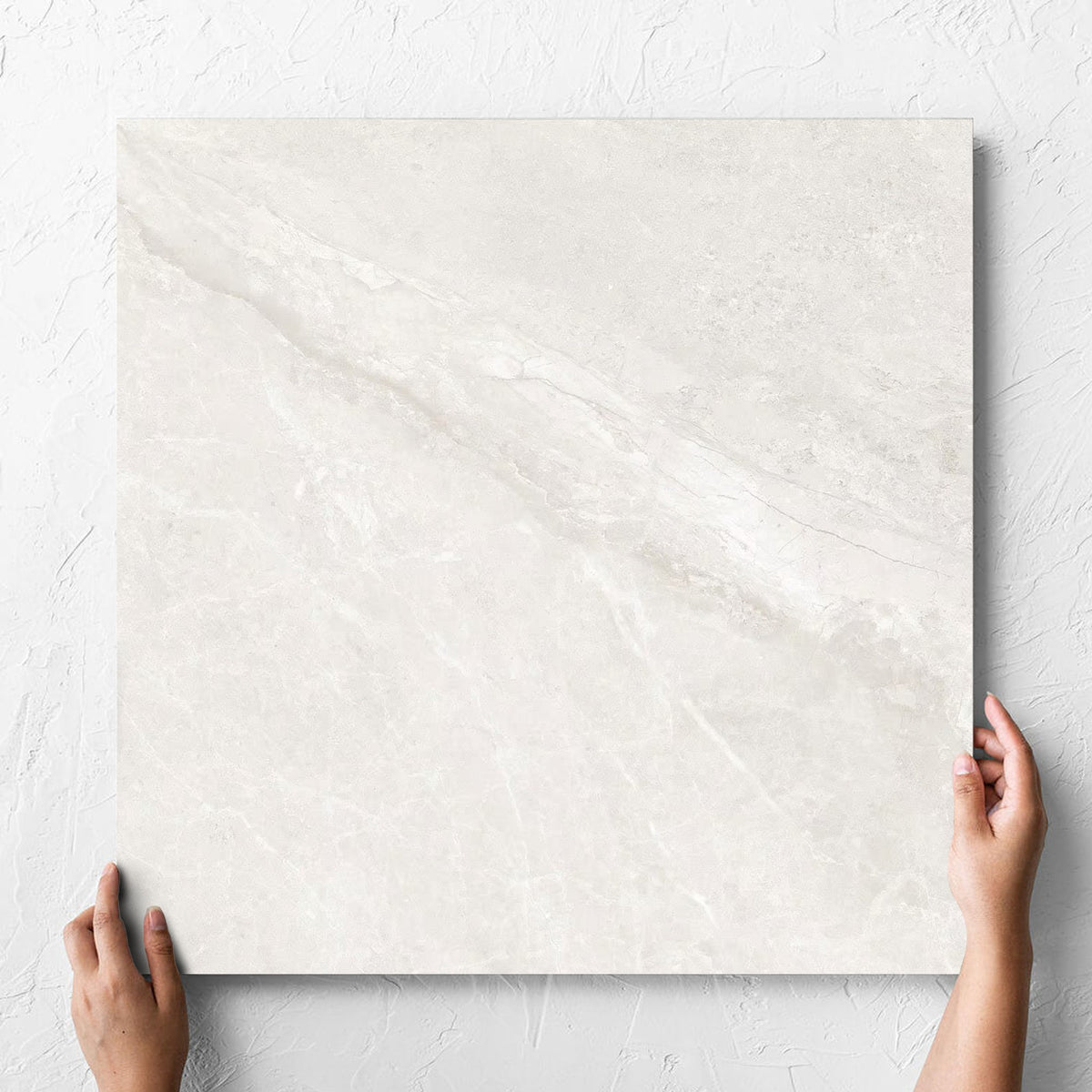 Hand holding a single Alpen Stone White Lappato 600x600mm tile against a white rendered wall, showing the tile surface