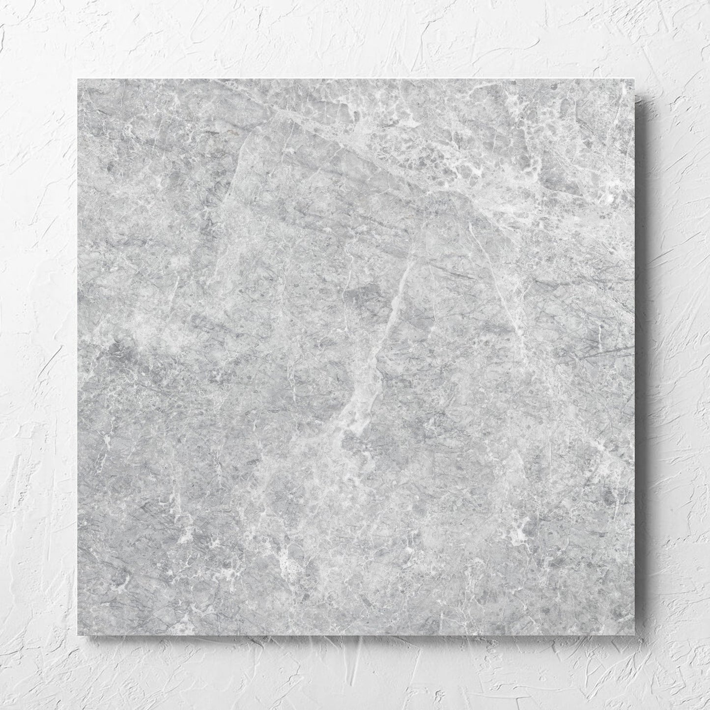 Antalya Silver Matt 600x600mm tile laid flat on a white rendered wall, showing the matt surface