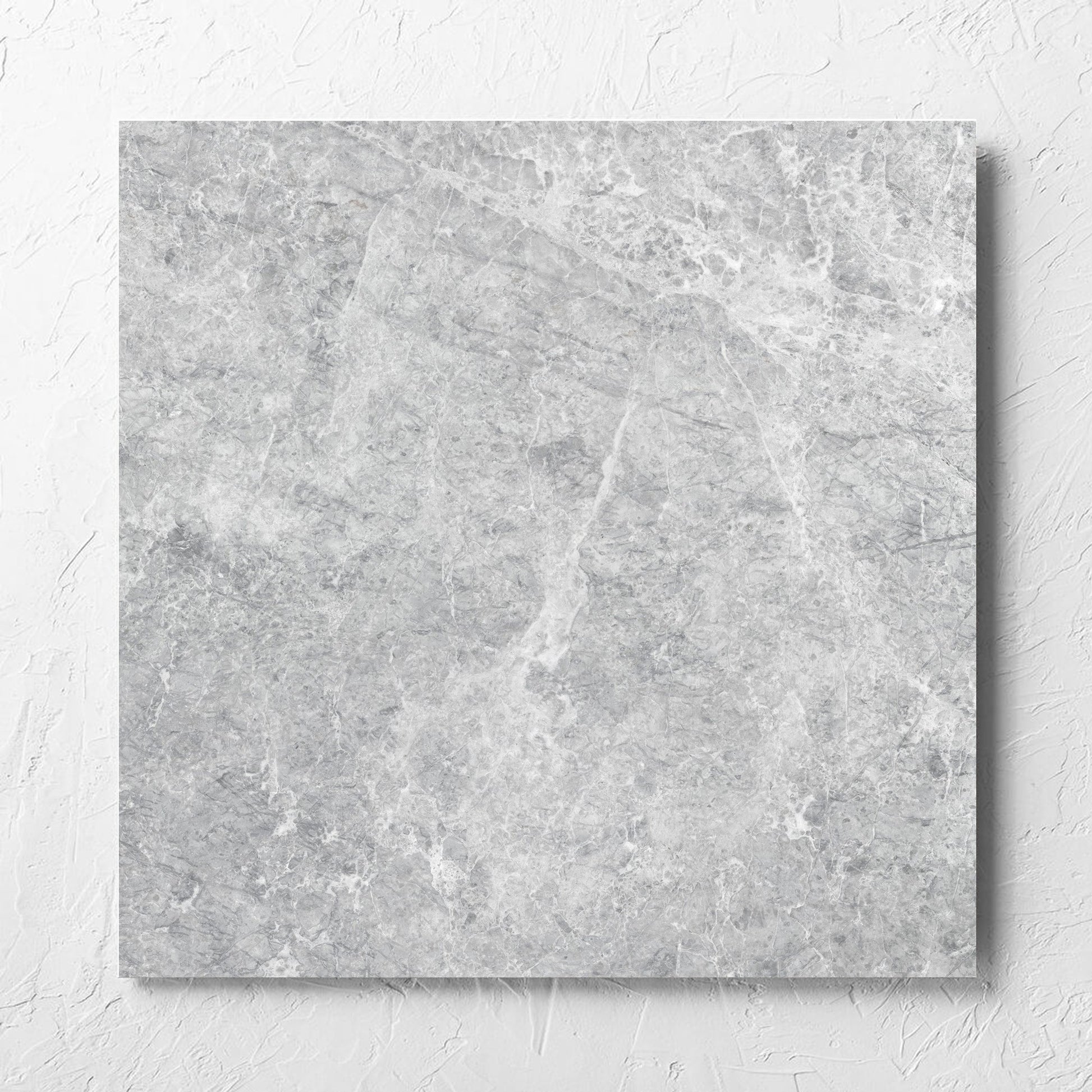 Antalya Silver Matt 600x600mm tile laid flat on a white rendered wall, showing the matt surface