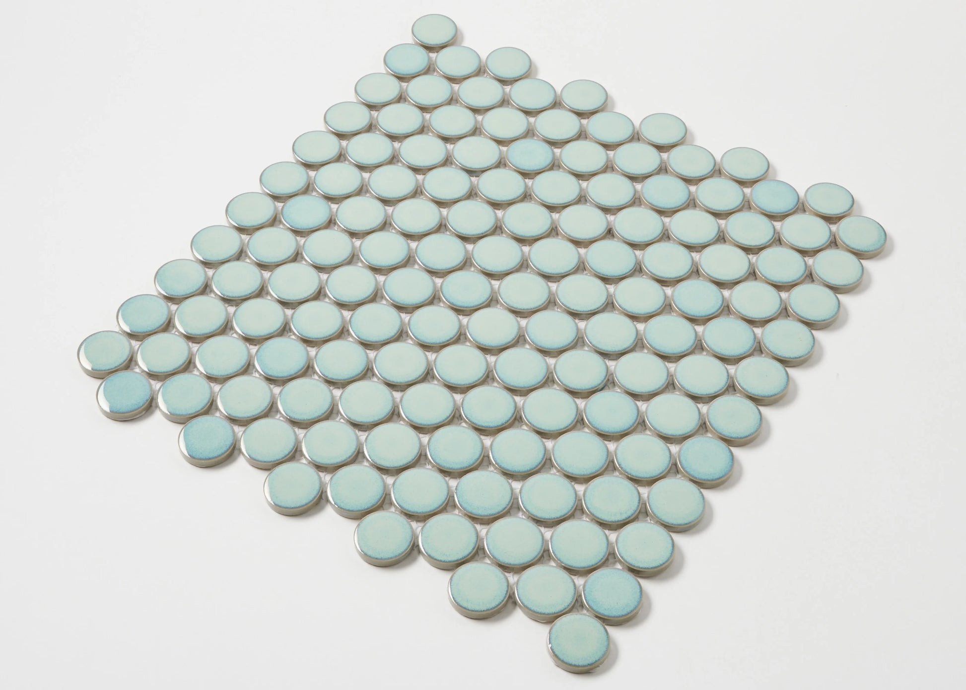 A diamond-shaped mosaic sheet of Antique Green Gloss Glazed Porcelain Penny Round 28mm Diameter tiles displaying a soft mint-green glazed finish arranged in neat circular rows.