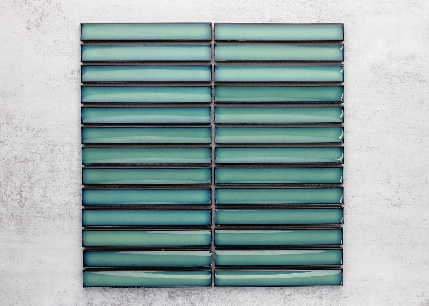 Two mesh-mounted sheets of Antique Medium Green Gloss Concave Porcelain Glazed Finger 20x145mm tiles displayed flat, showing the glossy teal-green elongated strips with dark grout lines.