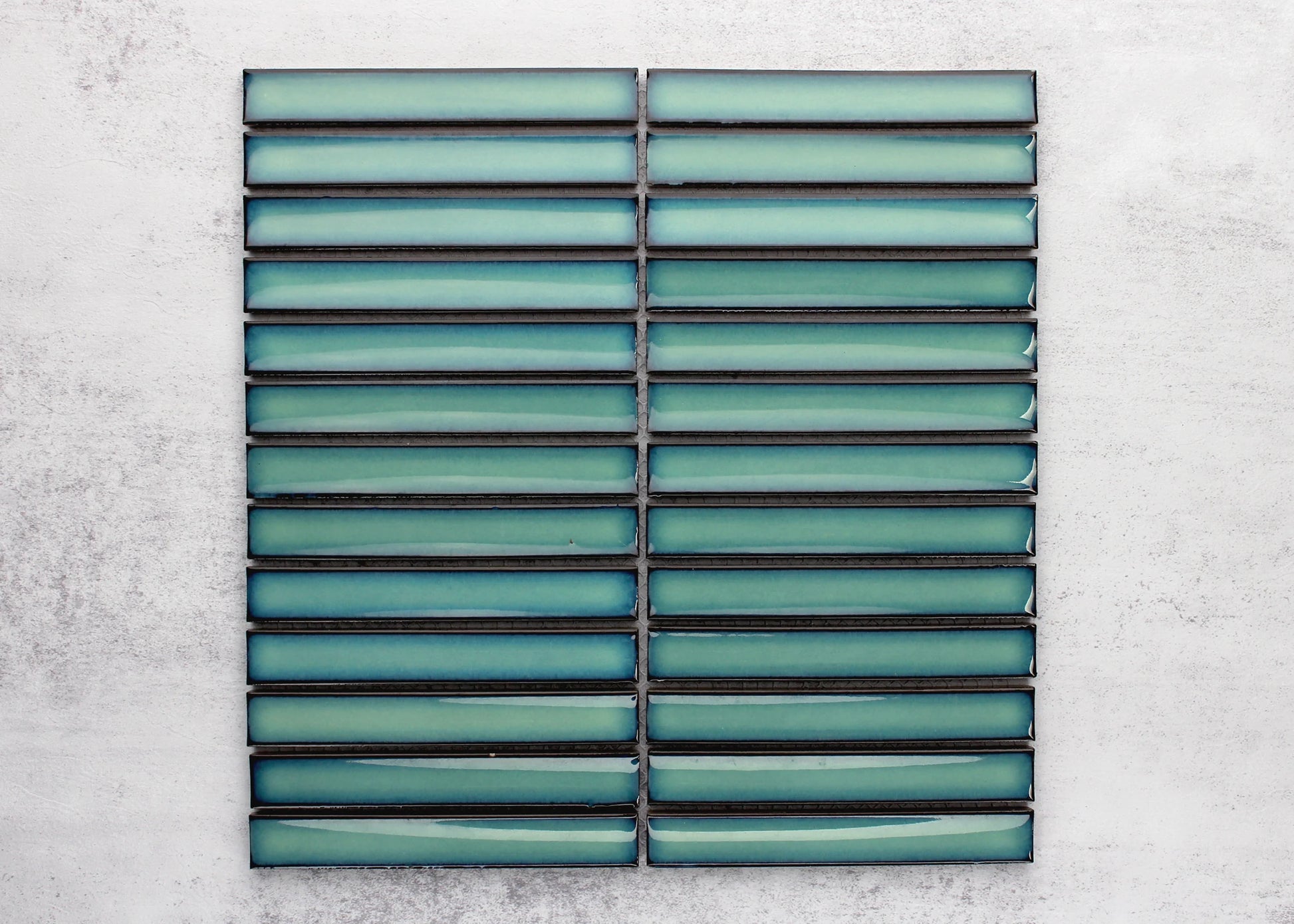 Two mesh-mounted sheets of Antique Medium Green Gloss Concave Porcelain Glazed Finger 20x145mm tiles displayed flat, showing the glossy teal-green elongated strips with dark grout lines.