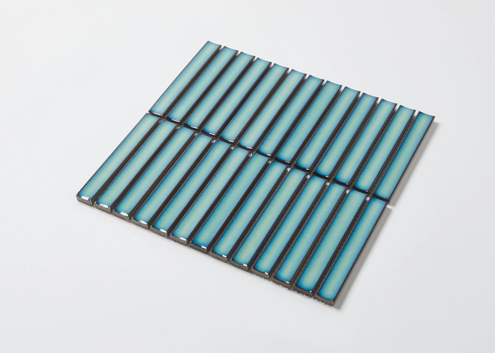 Pack shot of Antique Medium Green Gloss Concave Porcelain Glazed Finger 20x145mm tiles arranged in a flat grid, showcasing their elongated concave profile and blue-green gloss finish.