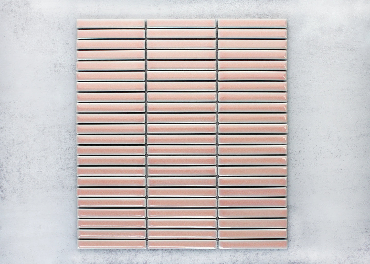 Pack shot of Antique Pale Pink Gloss Porcelain Glazed KitKat 12x92mm tiles arranged in a stacked horizontal pattern with white grout lines on a grey background.