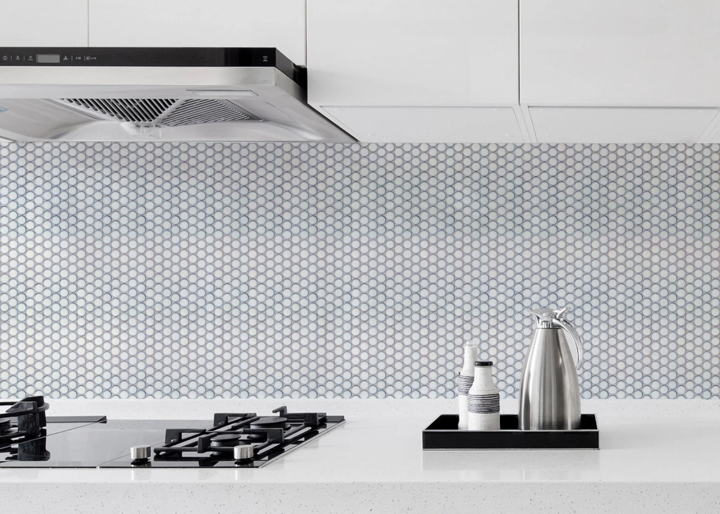 Antique White Gloss Glazed Porcelain Penny Round 28mm Diameter tiles installed as a kitchen splashback behind a black gas cooktop and stainless steel range hood.