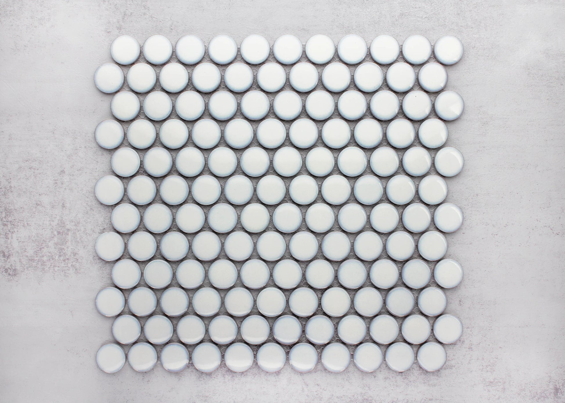 A flat lay pack shot of Antique White Gloss Glazed Porcelain Penny Round 28mm Diameter tiles arranged in a neat mosaic sheet against a grey background.